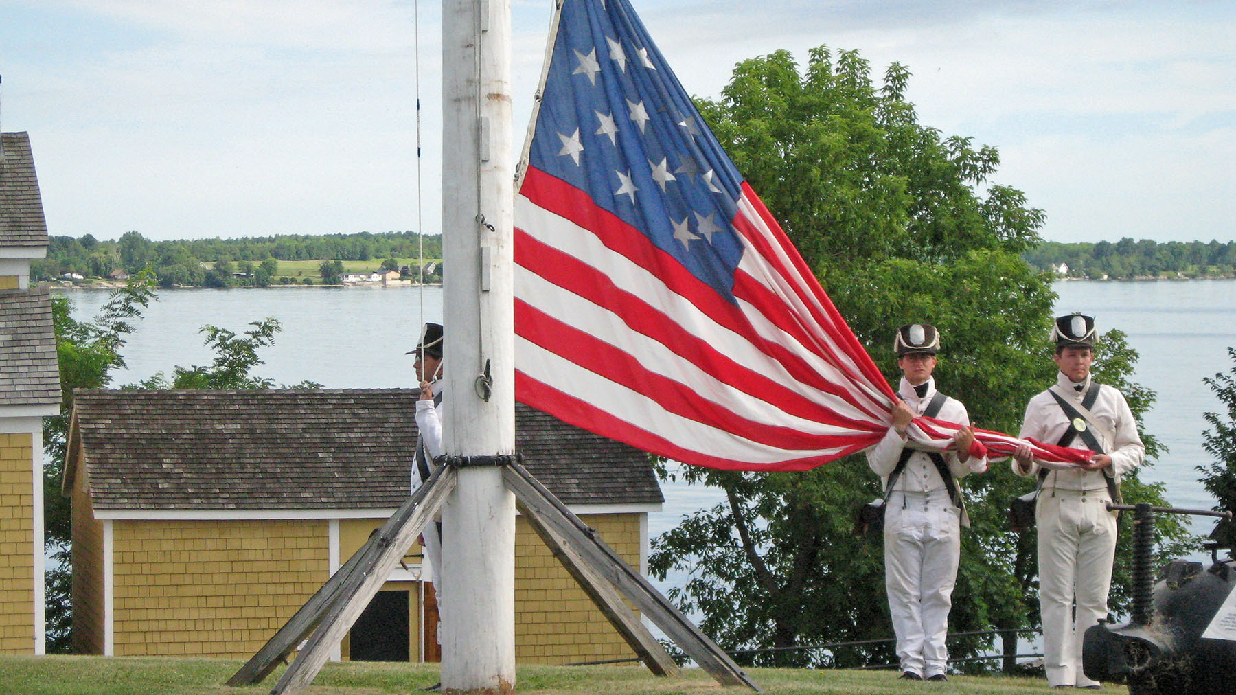 Photo of reenactors at the Sackets Harbor Battlefield lowering the American Flag