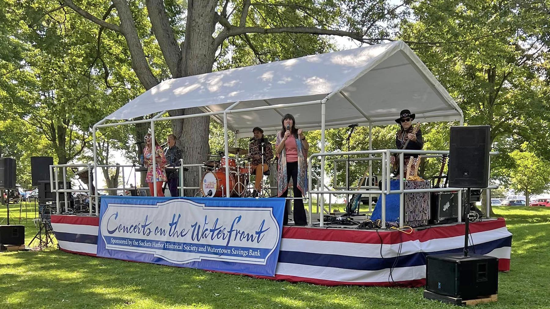 Color photo of The Large Flowerheads band performing during the 2023 Concerts on the Waterfront series at the Sackets Harbor Battlefield