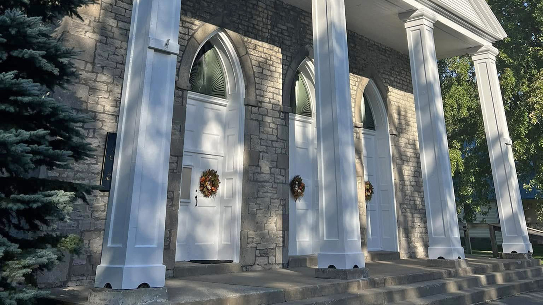 Cropped exterior photo of the entrance at the Old Stone Chapel in Sackets Harbor in the spring