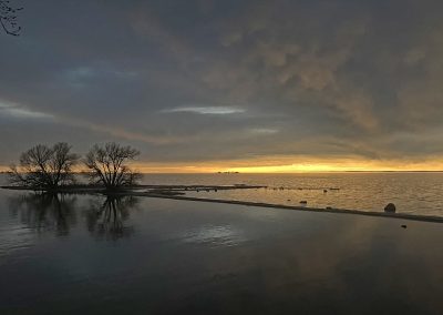 Looking out over Lake Ontario in the spring just after sunset and a small island on the left, 2024 Photo Contest winner in the Four Seasons Category by Maura Smith