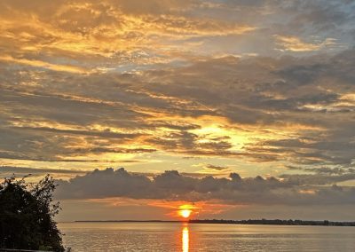 Portrait photo of a sunset looking out over Lake Ontario from the Battlefield; 2024 Photo Contest winner in the Sunset category, by Marcia Kall