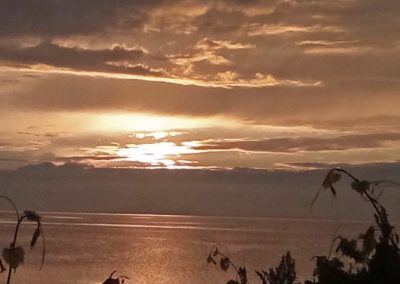 Landscape photo of a sunset over Lake Ontario, taken from the shore in Sackets Harbor; 2024 Photo Contest winner in the Under 18 Sunset category, by Genevieve Hughes