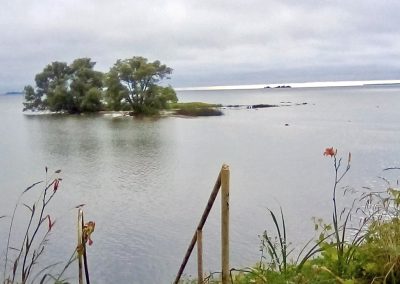 Landscape photo of a small island with trees just off the shore in Lake Ontario; 2024 Photo Contest winner in the Under 18, Water and Boats category, by Joseph Hughes