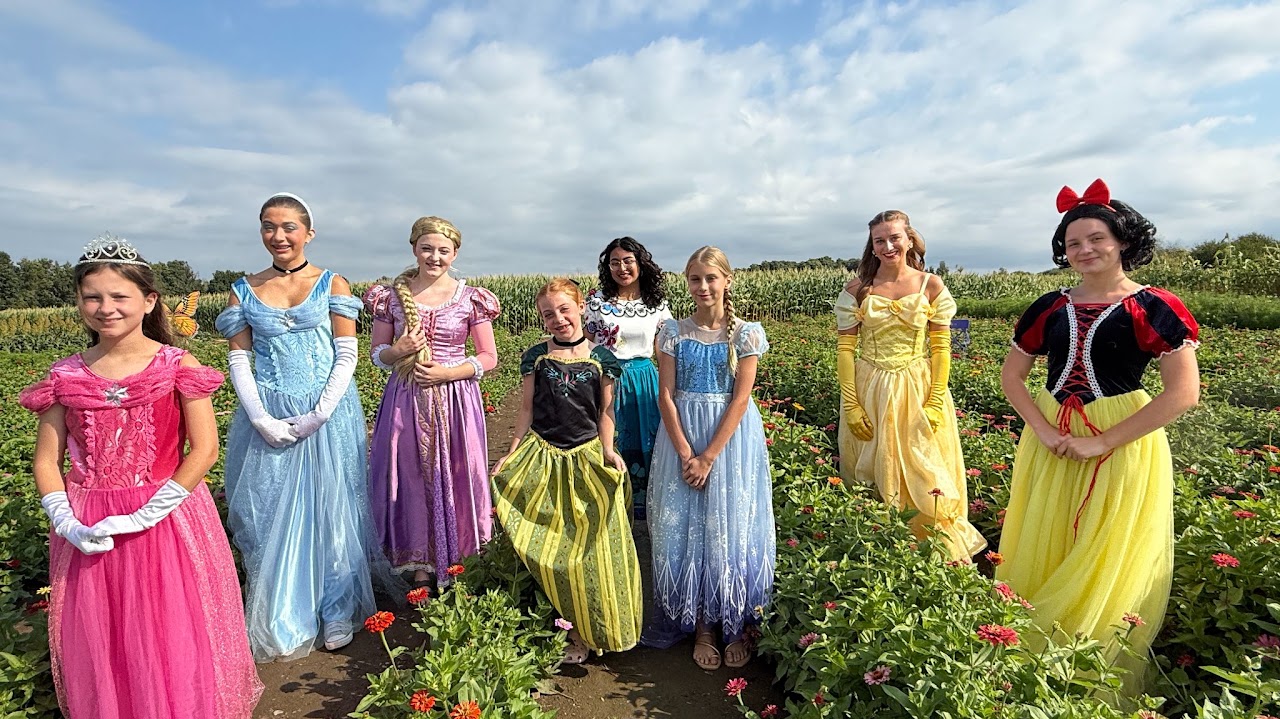 Color photo of young women dressed as princesses in a field at Old McDonald's Farm in Sackets Harbor