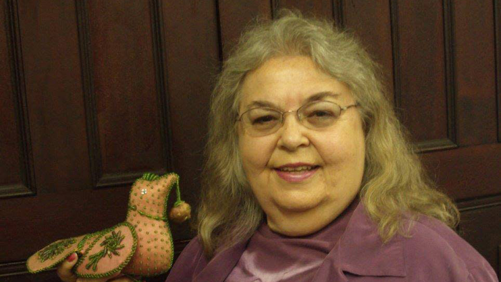 Photo of Dolores Elliott holding a handmade, beaded bird
