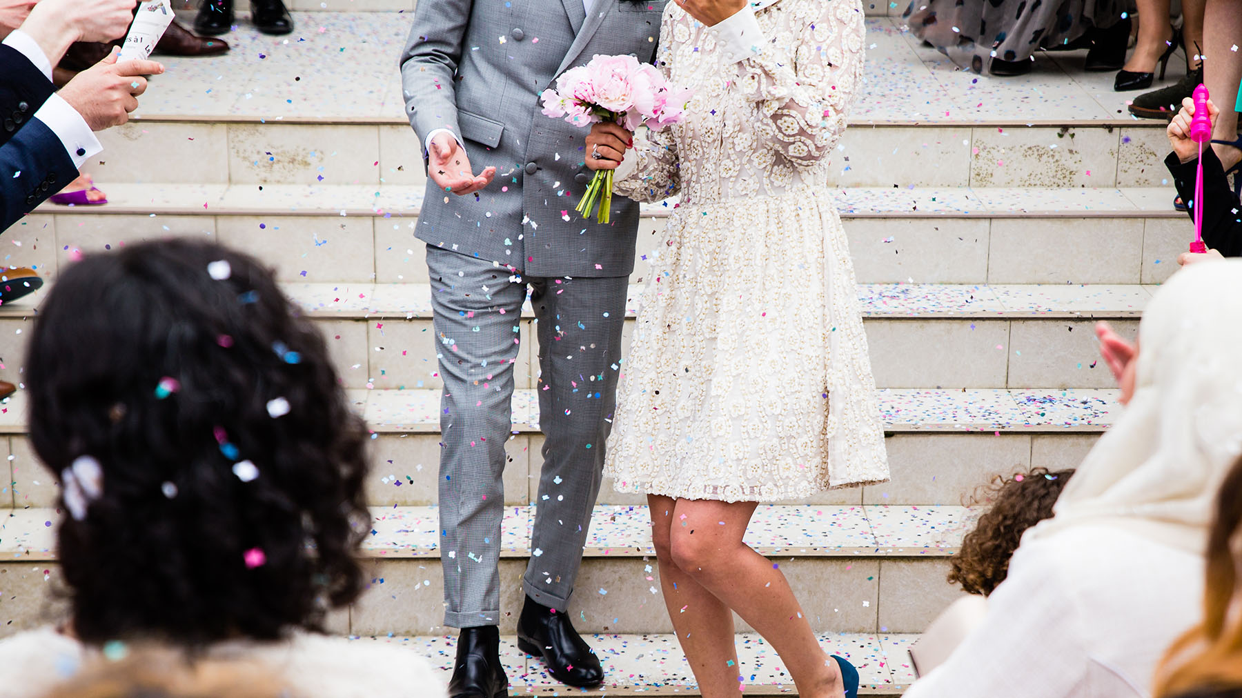 Color photo of a bride and groom standing on steps after wedding with confetti; Public domain image, courtesy of RawPixel.com